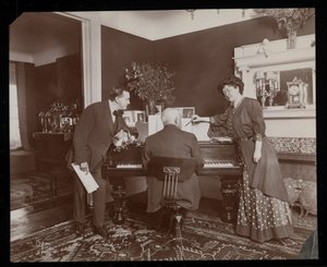 Clara De Regand apontando para uma pontuação enquanto um homem toca piano, 1910 (impressão de gelatina de prata)